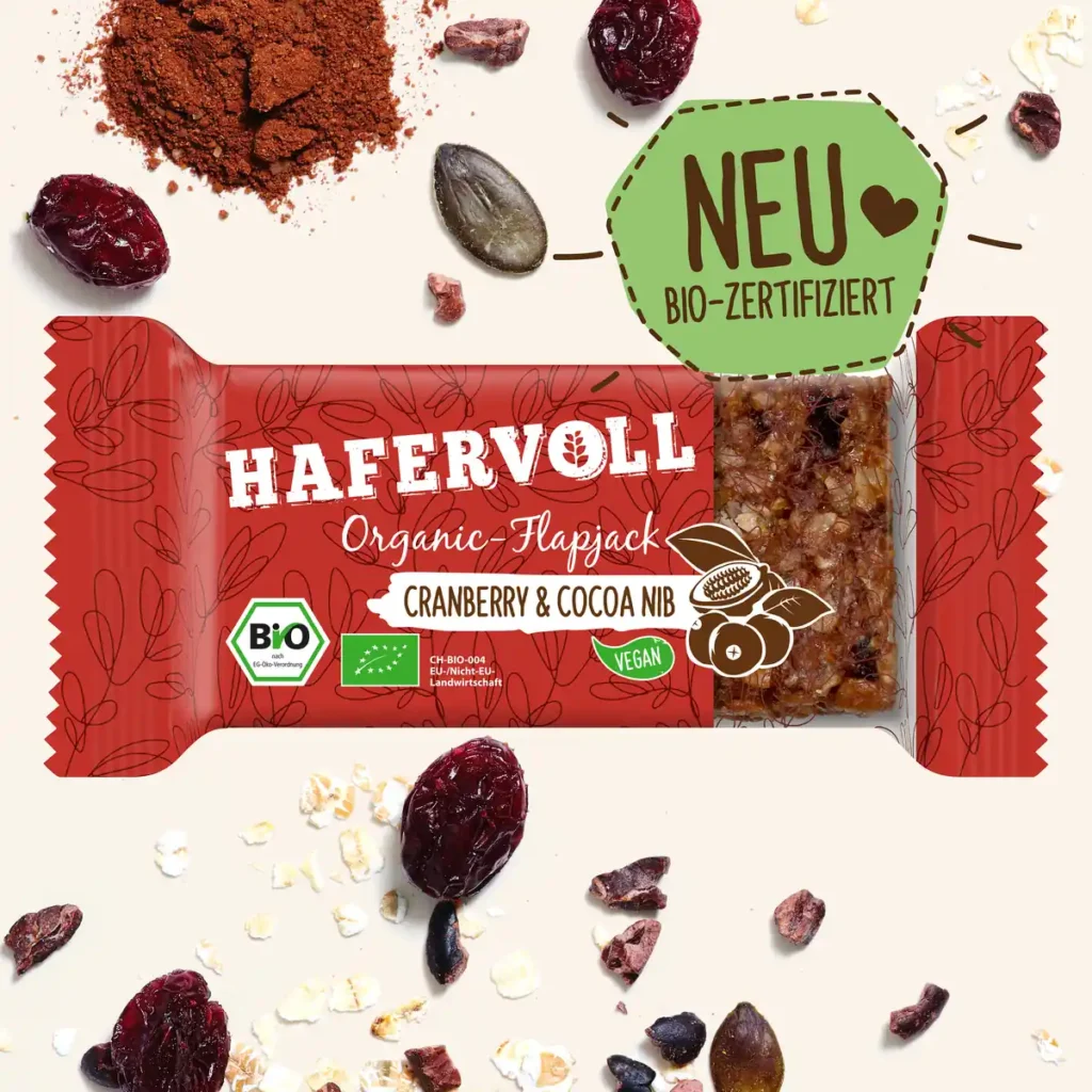 HAFERVOLL Organic Flapjack Cranberry & Cocoa Nib 60g – Riegel in der Verpackung mit Cranberrys und Kakaonibs
